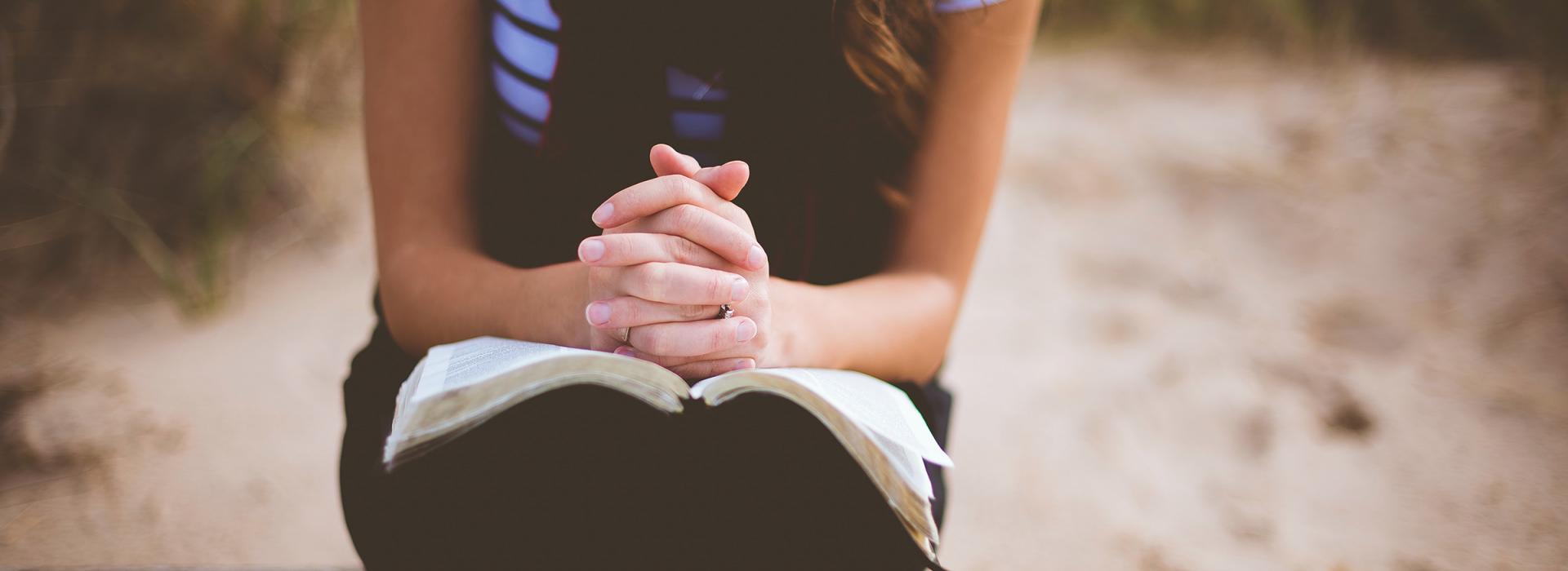 Faru die mit gefalteten Händen und ihrer Bibel da sitzt
