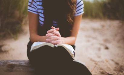 Faru die mit gefalteten Händen und ihrer Bibel da sitzt