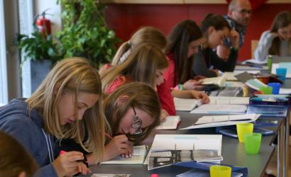 Jugendliche sitzen an Tischen vertieft in eine Aufgabe