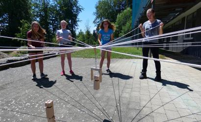 Eine Gruppe von Teilnehmern führt eine erlebnispädagogische Maßnahme durch